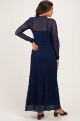 woman wearing a navy blue lace maternity maxi dress with long sleeves and a flowing skirt, showing a baby bump
