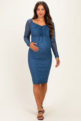 woman wearing a blue lace maternity dress with long sleeves and a fitted silhouette, showcasing her baby bump