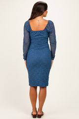 woman wearing a dark blue lace maternity dress with long sleeves and a fitted silhouette, showing off a baby bump from the back