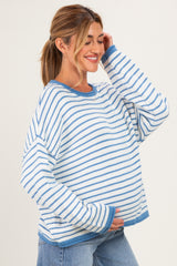 woman wearing a white and blue striped maternity sweater and holding her baby bump