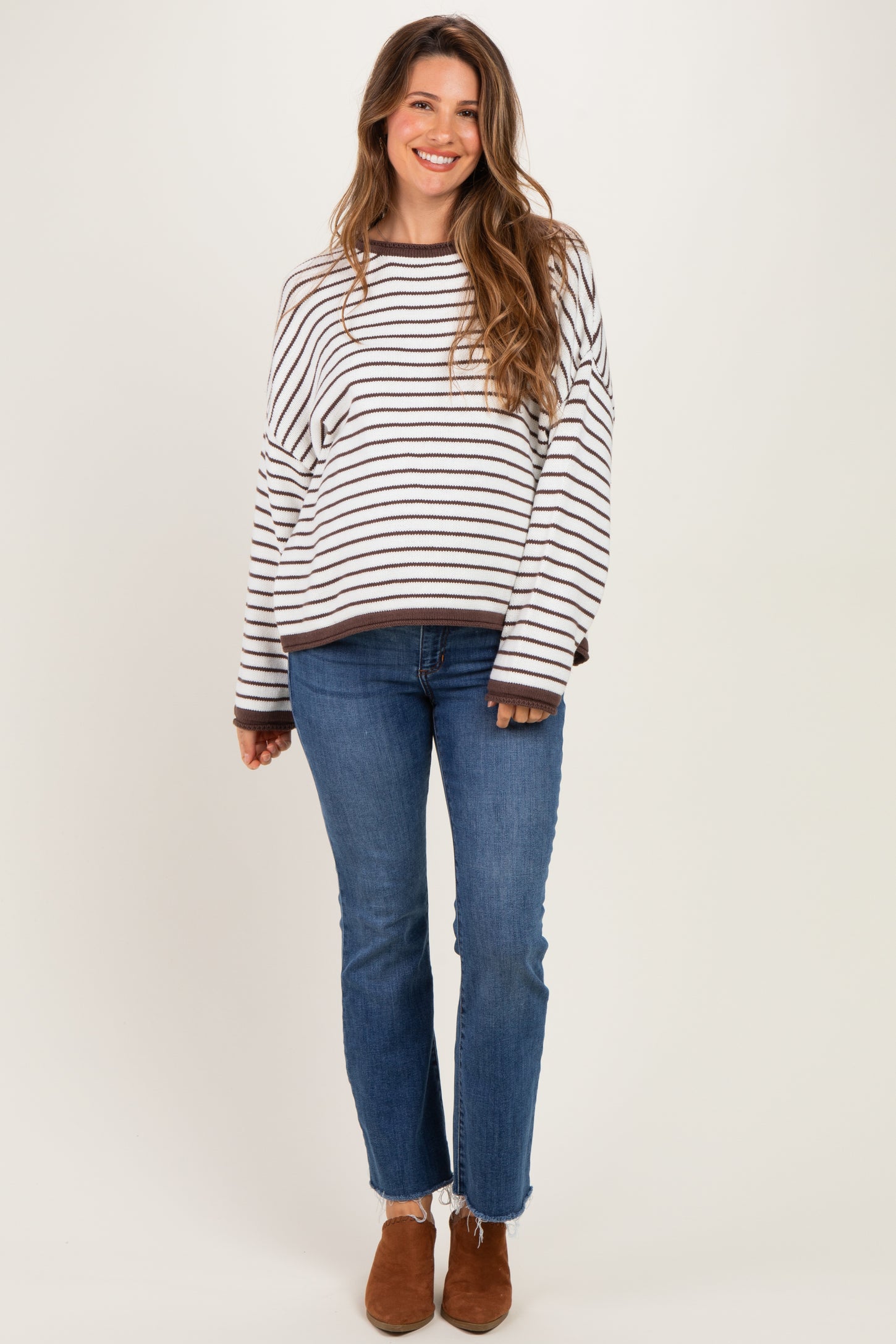 woman wearing a striped oversized maternity sweater with long sleeves and a relaxed fit paired with jeans