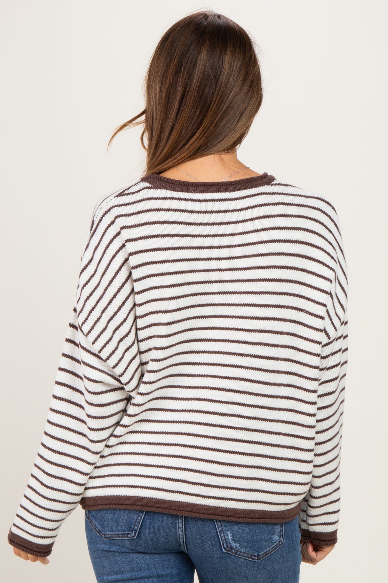 woman wearing a striped maternity sweater in white and brown, showing the back with relaxed fit and long sleeves