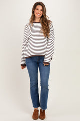woman wearing a striped oversized maternity sweater with long sleeves and a relaxed fit paired with jeans