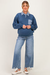 woman wearing a blue maternity sweatshirt with checkered pocket and collar, paired with wide-leg jeans