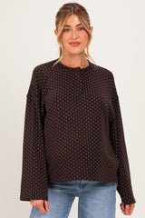woman wearing a brown polka dot maternity top with button details and long sleeves, styled with light blue jeans