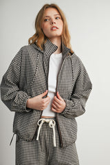woman wearing a brown and white checkered oversized jacket with a zip front and a white t-shirt underneath