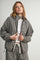 woman wearing a brown and white checkered oversized jacket with a zip front and a white t-shirt underneath