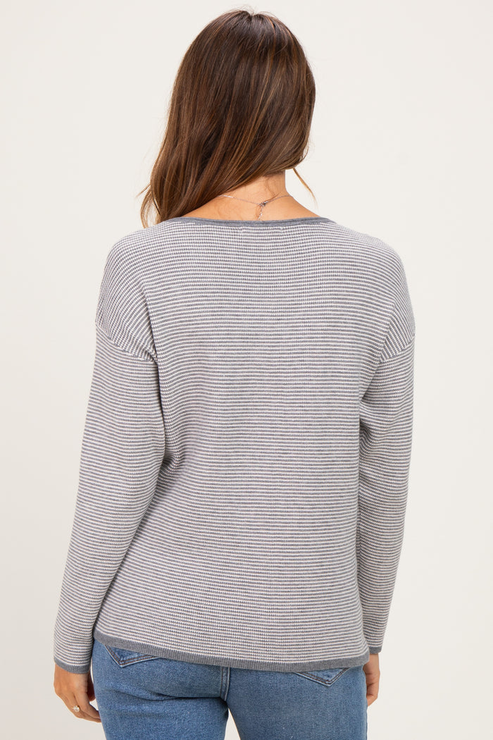 woman wearing a gray striped maternity sweater, shown from the back, paired with blue jeans