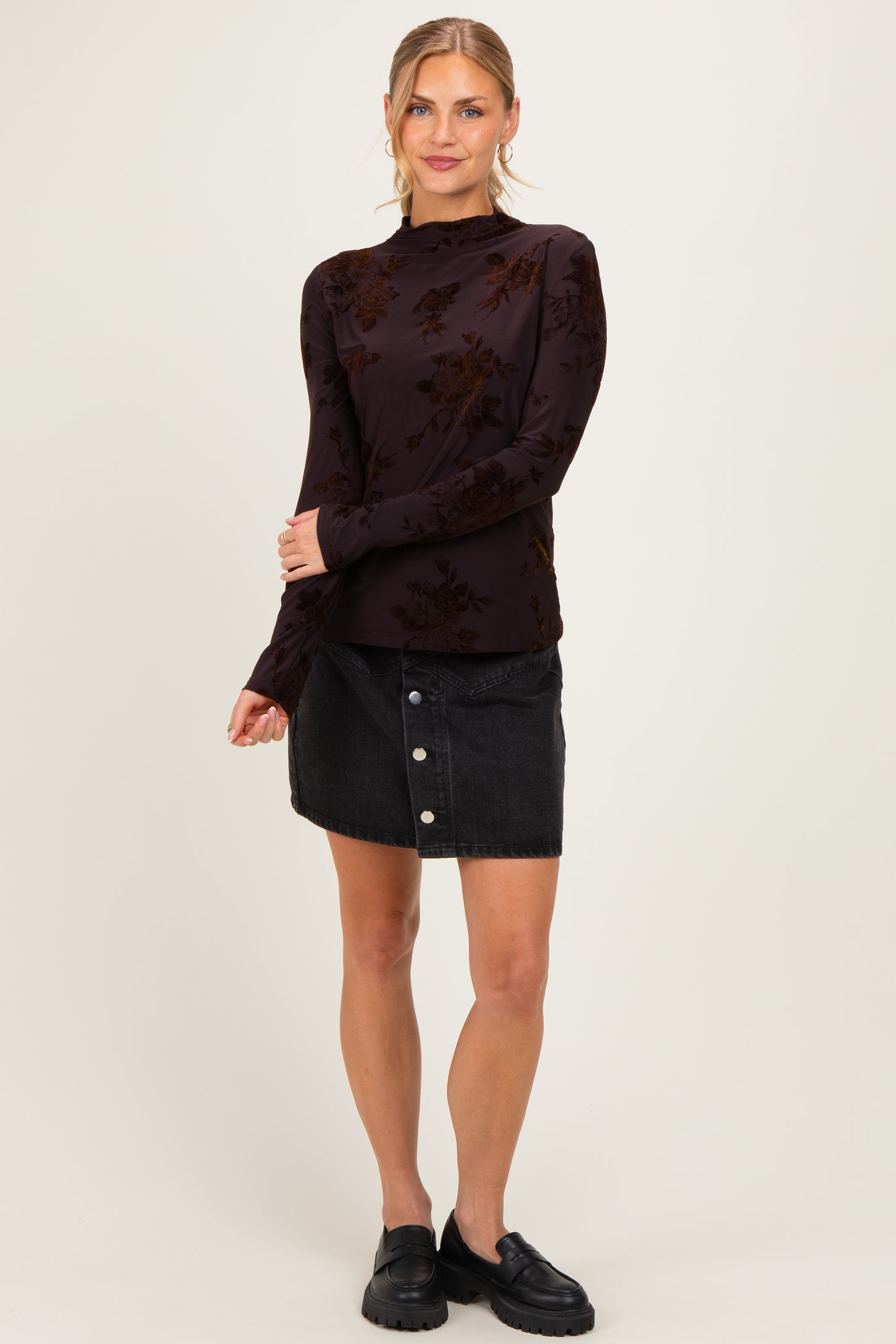 woman wearing a dark floral long sleeve top and a black denim button-up skirt