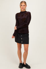 woman wearing a dark floral long sleeve top and a black denim button-up skirt