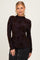 woman wearing a dark floral long sleeve top with a high neckline and black skirt