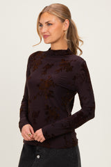 woman wearing a dark purple long sleeve top with floral velvet design and high neckline