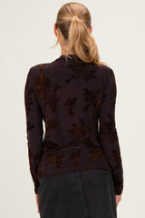 woman wearing a dark floral long sleeve top, seen from the back with a fitted style and subtle texture