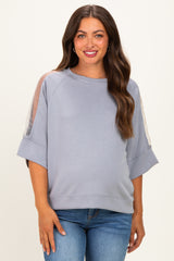 woman wearing a light grey maternity sweatshirt with sheer panels on the sleeves and a relaxed fit, smiling at the camera