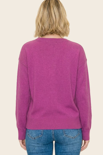woman wearing a back view of a magenta oversized sweater paired with blue jeans