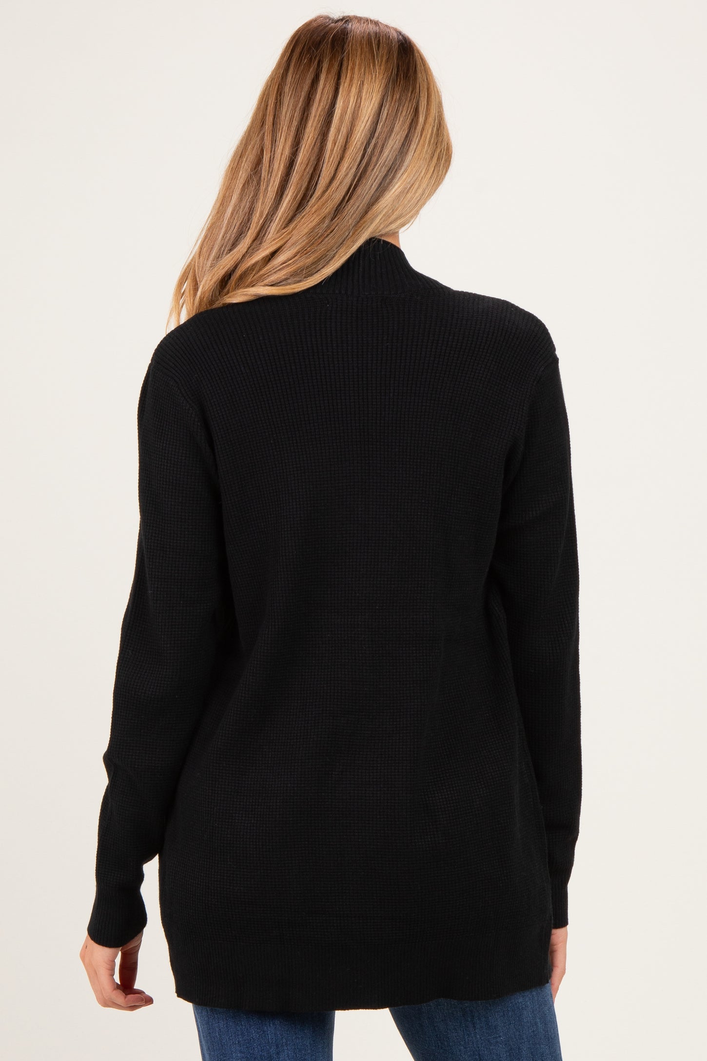 woman wearing a black maternity sweater with a relaxed fit, view from the back, showcasing a longer length