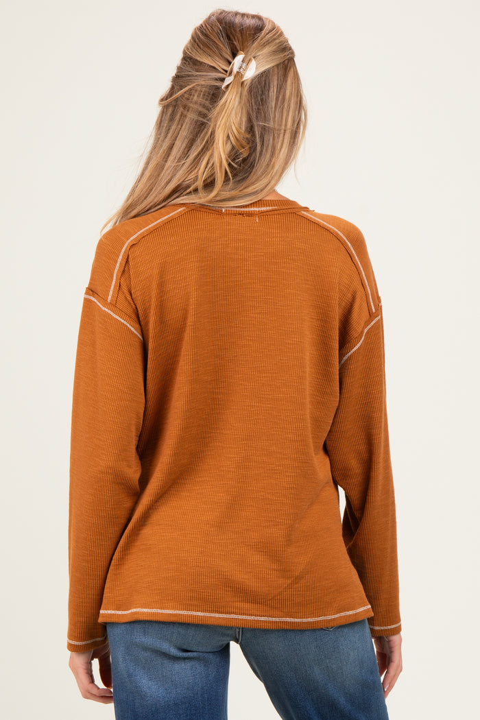 woman wearing a rust colored maternity long sleeve top, viewed from the back with casual style and relaxed fit