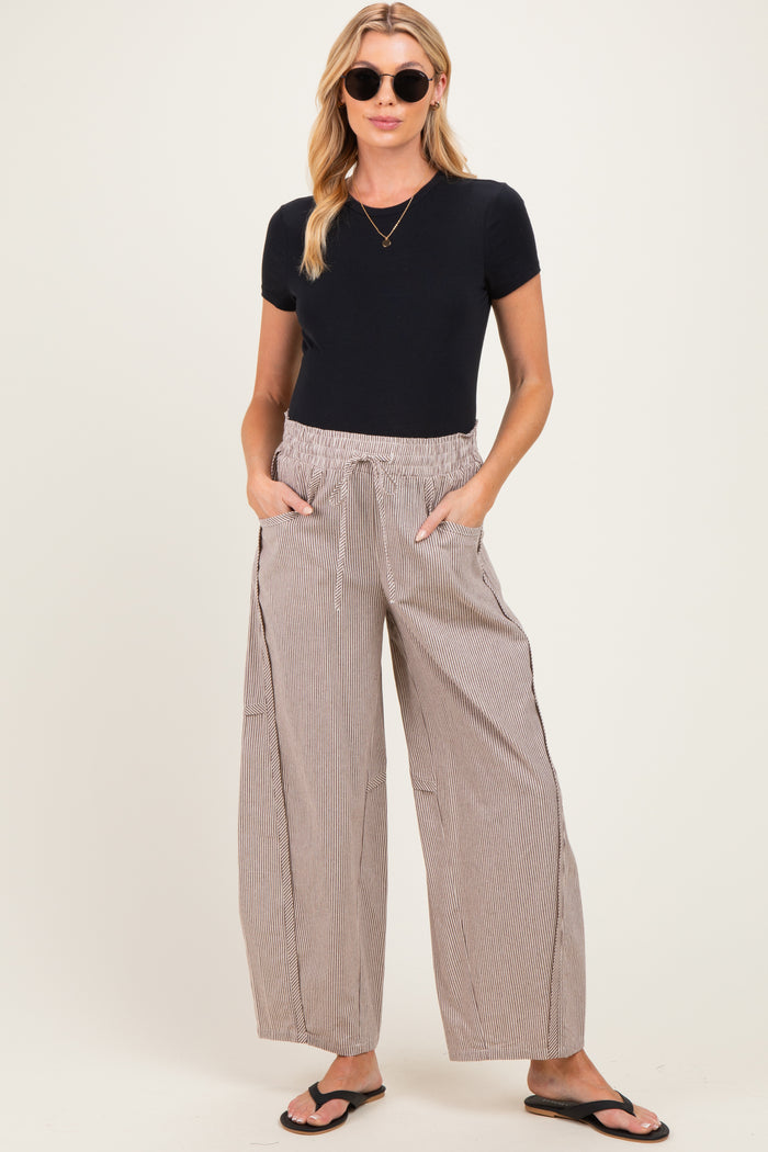 woman wearing a black short sleeve maternity top and relaxed striped maternity pants with pockets