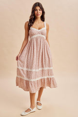 woman wearing a light pink floral maxi dress with lace detailing and a tiered hem