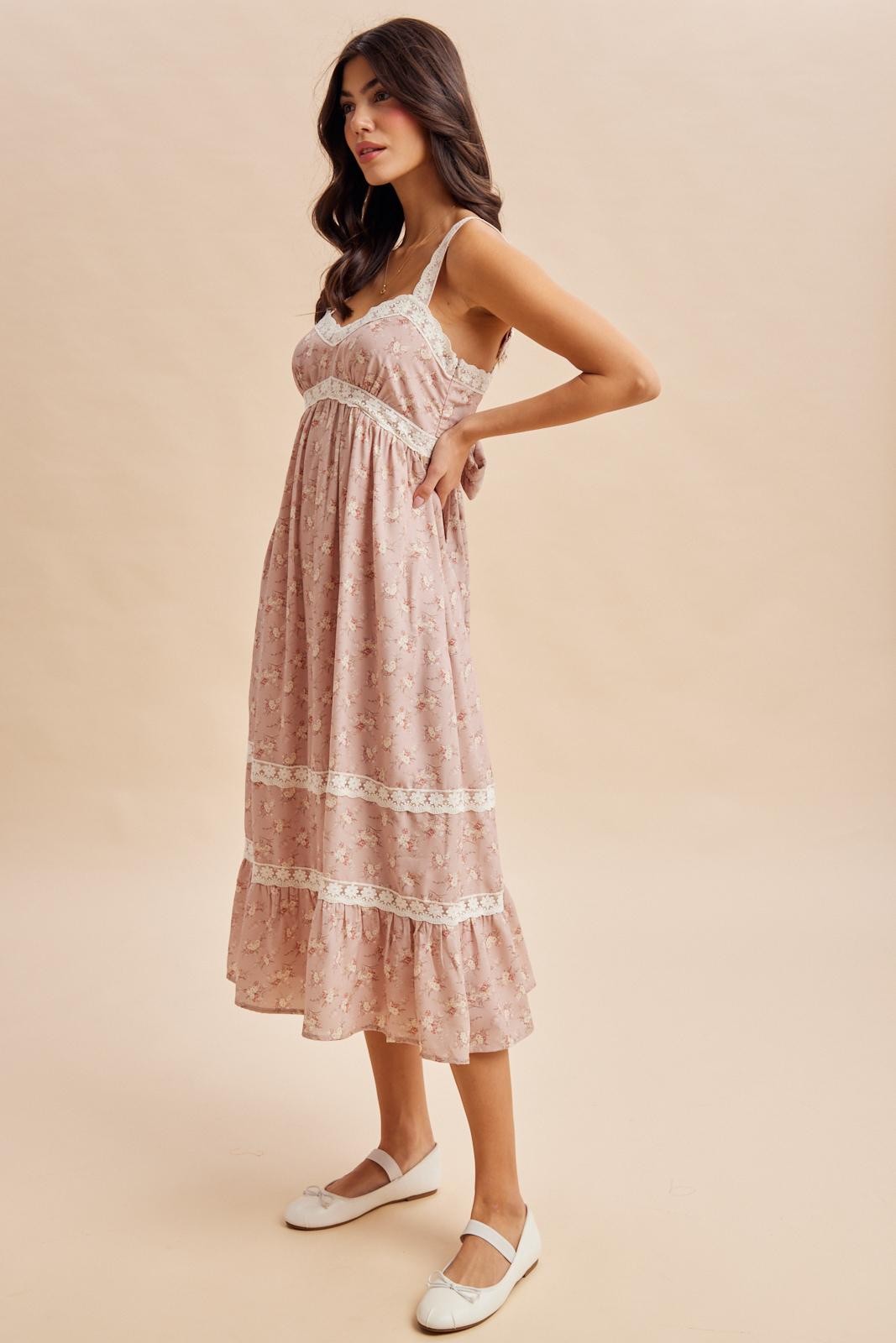 woman wearing a pink floral midi dress with lace trim and adjustable straps, styled with white flats
