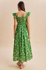 woman wearing a green floral maxi dress with ruffled sleeves and a smocked back, seen from behind