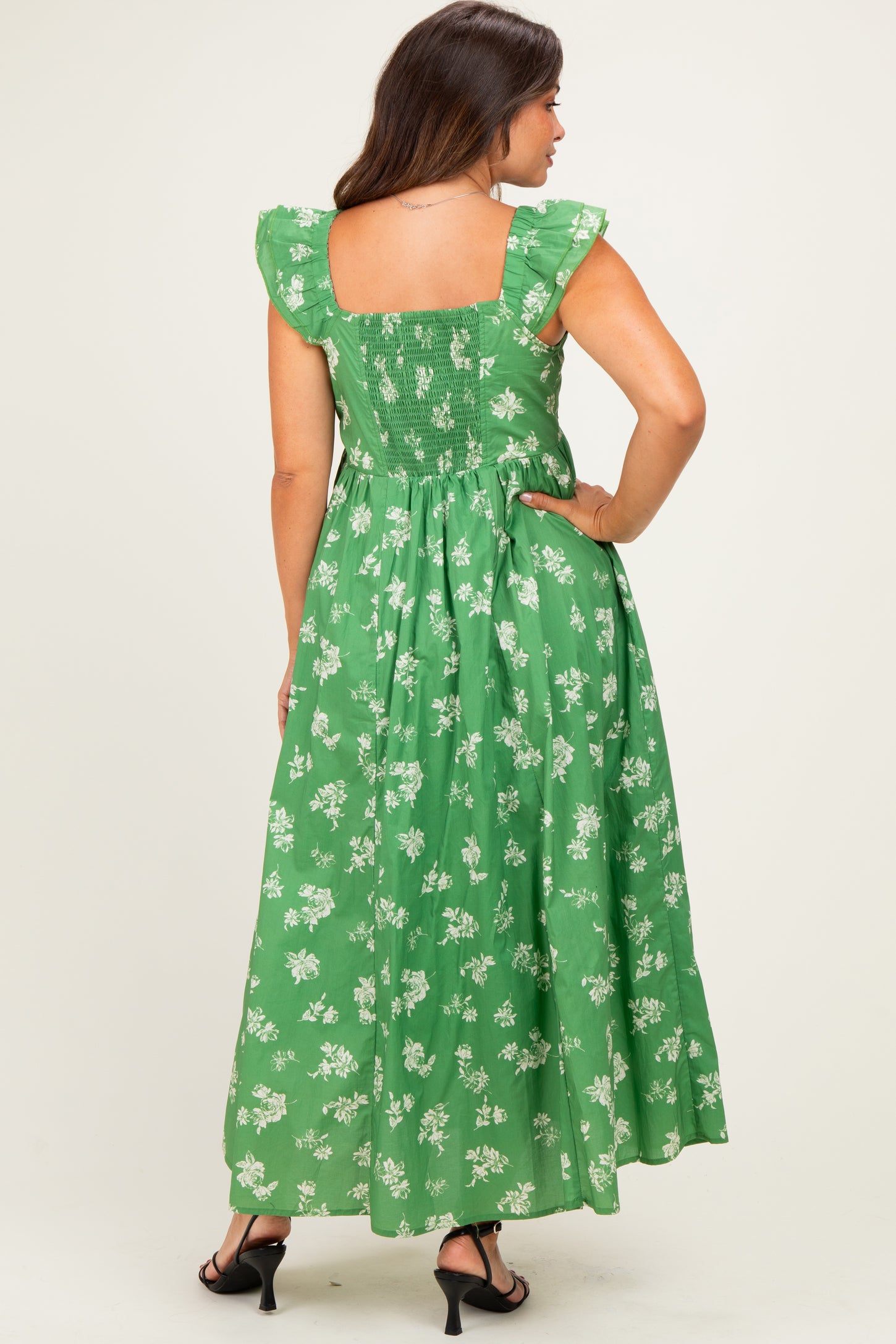 woman wearing a green floral maternity maxi dress with ruffled sleeves and a smocked back