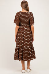 woman wearing a brown polka dot maternity dress with short sleeves and a tiered skirt, showing a baby bump from the back