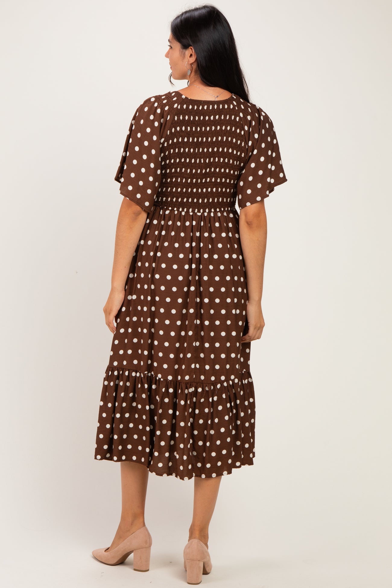 woman wearing a brown polka dot midi dress with puff sleeves and a ruffled hem, viewed from the back