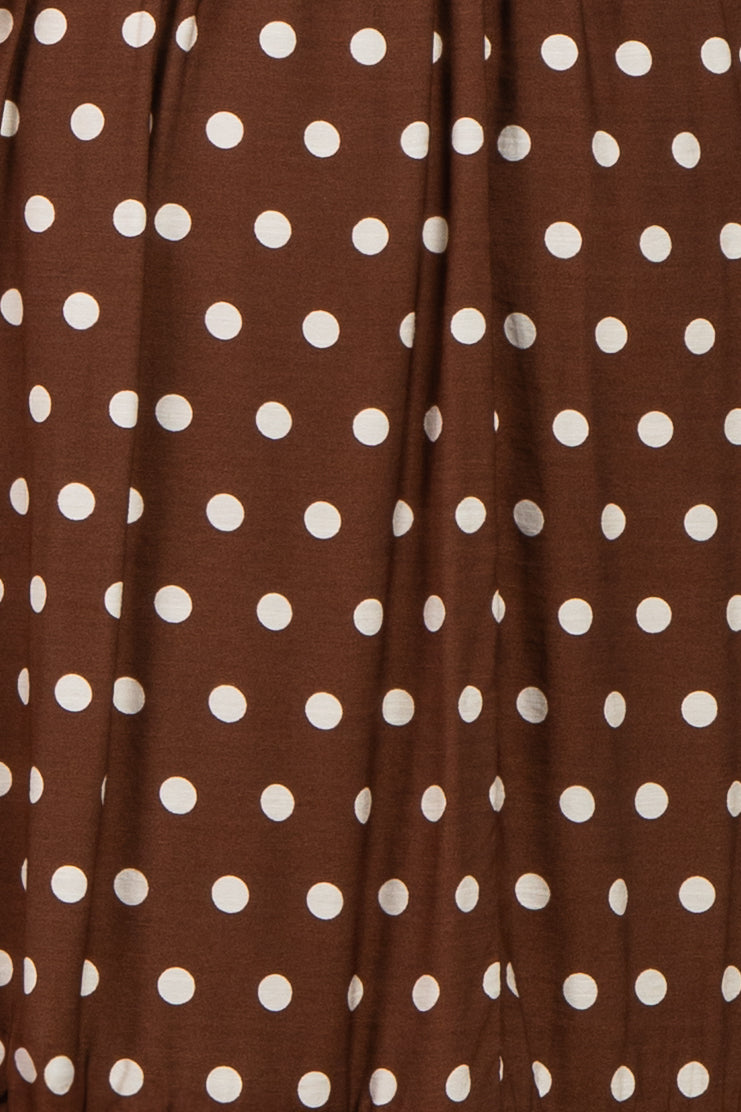brown polka dot fabric with large white dots in a flowing style