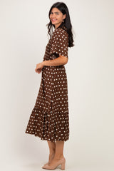 woman wearing a brown polka dot midi dress with a tiered skirt and short sleeves, standing in profile