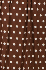 brown polka dot fabric with large white dots in a flowing style
