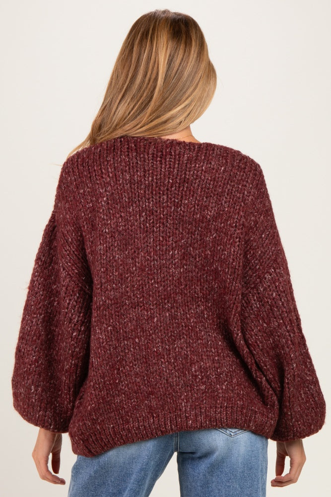 woman wearing a burgundy chunky knit maternity sweater with balloon sleeves, seen from the back