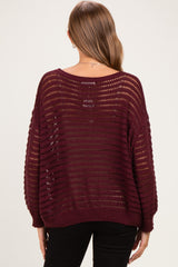 woman wearing a burgundy open knit maternity sweater with a relaxed fit and long sleeves, showcasing the back view