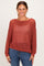 woman wearing a rust open-knit sweater with a relaxed fit and long sleeves, paired with blue jeans