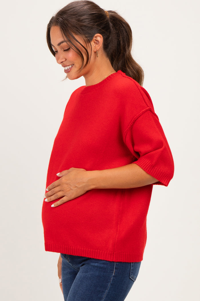 woman wearing a red short sleeve maternity sweater and holding her baby bump