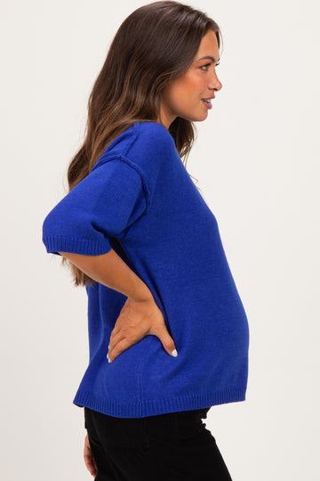 woman wearing a royal blue short sleeve maternity sweater and showing her baby bump