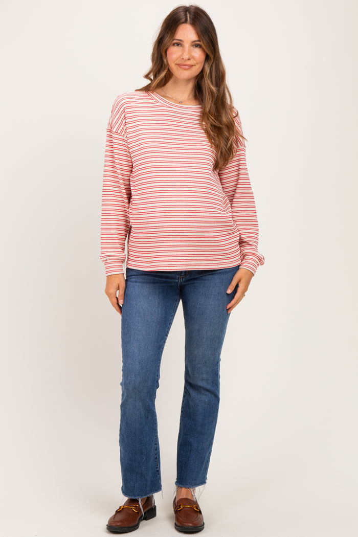 woman wearing a red and white striped maternity sweatshirt with long sleeves and blue jeans, showcasing her baby bump