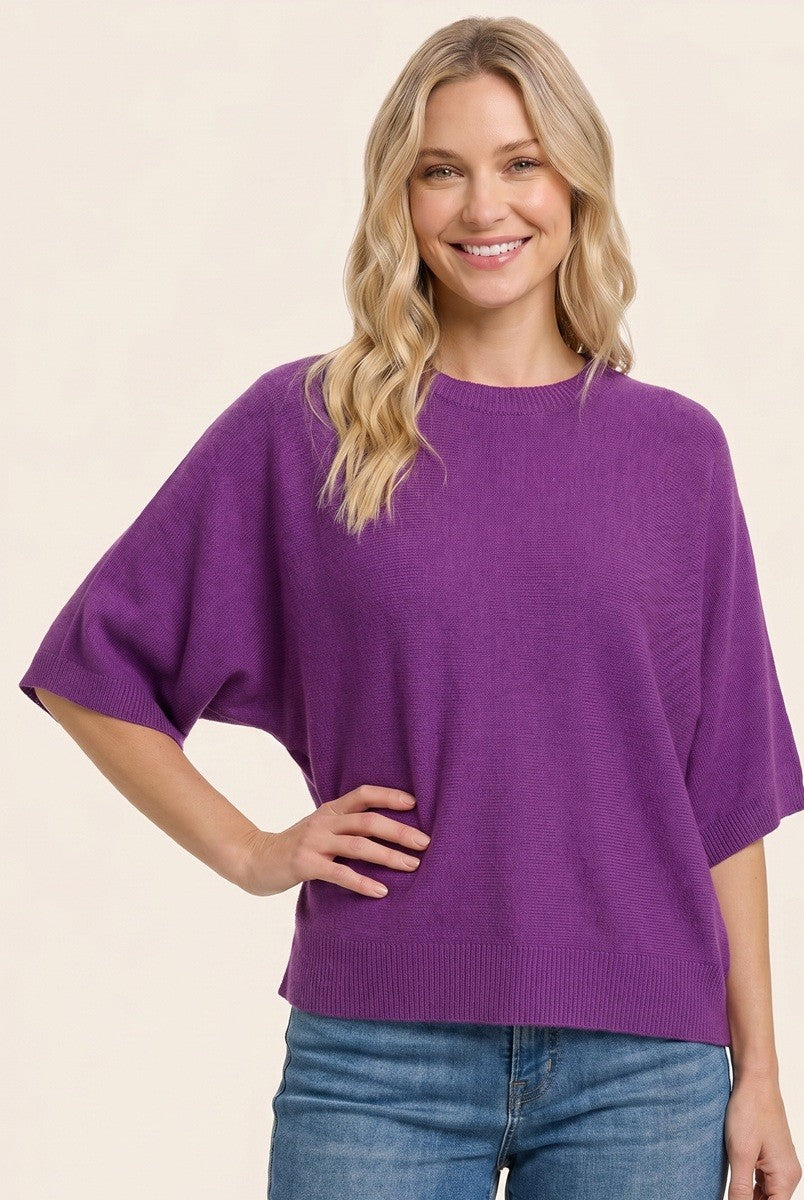 woman wearing a purple short sleeve sweater with a relaxed fit and smiling at the camera
