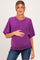 woman wearing a purple short sleeve maternity sweater and holding her baby bump