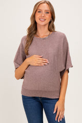 woman wearing a mauve short sleeve maternity sweater and holding her baby bump