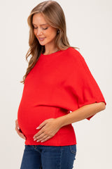woman wearing a bright red short sleeve maternity top and holding her baby bump