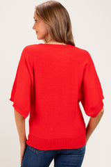 woman wearing a bright red short sleeve maternity sweater, showing the back view with a loose fit and ribbed hem