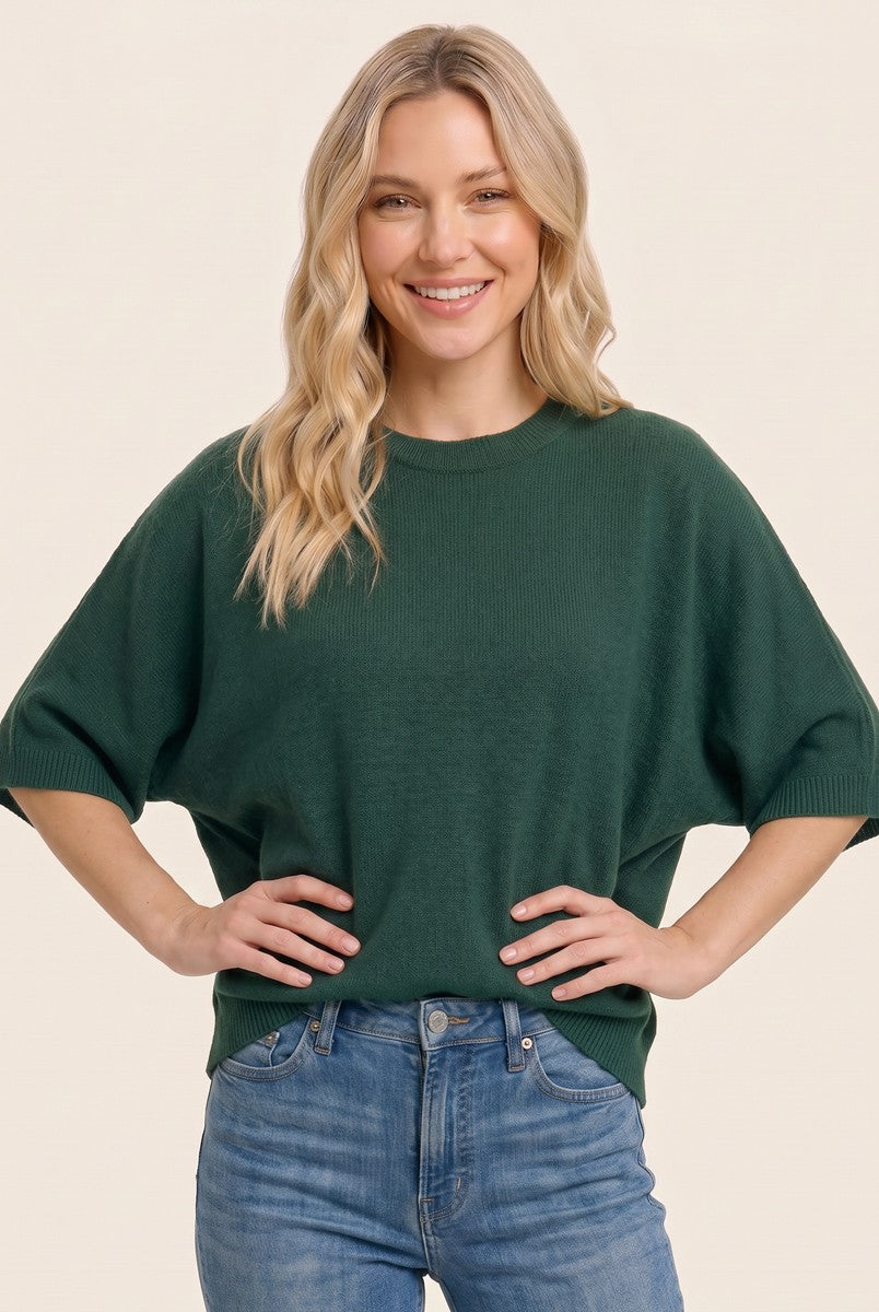 woman wearing a dark green oversized knit sweater and light blue jeans