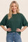 woman wearing a dark green oversized knit sweater and light blue jeans