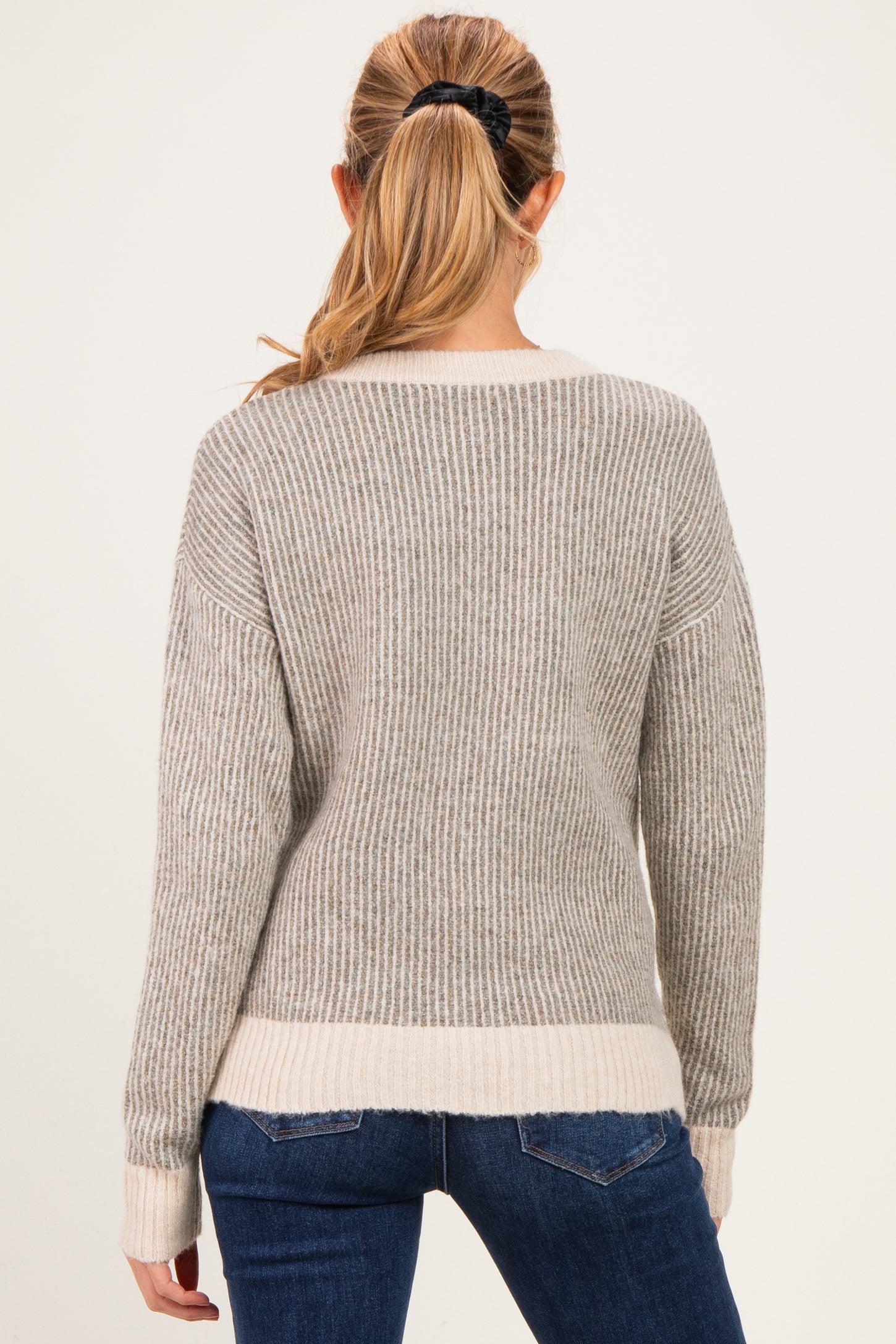 woman wearing a gray and cream striped maternity sweater, showing the back view and long sleeves