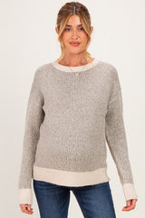 woman wearing a light gray striped maternity sweater with a neutral hem and cuffs, showing her baby bump