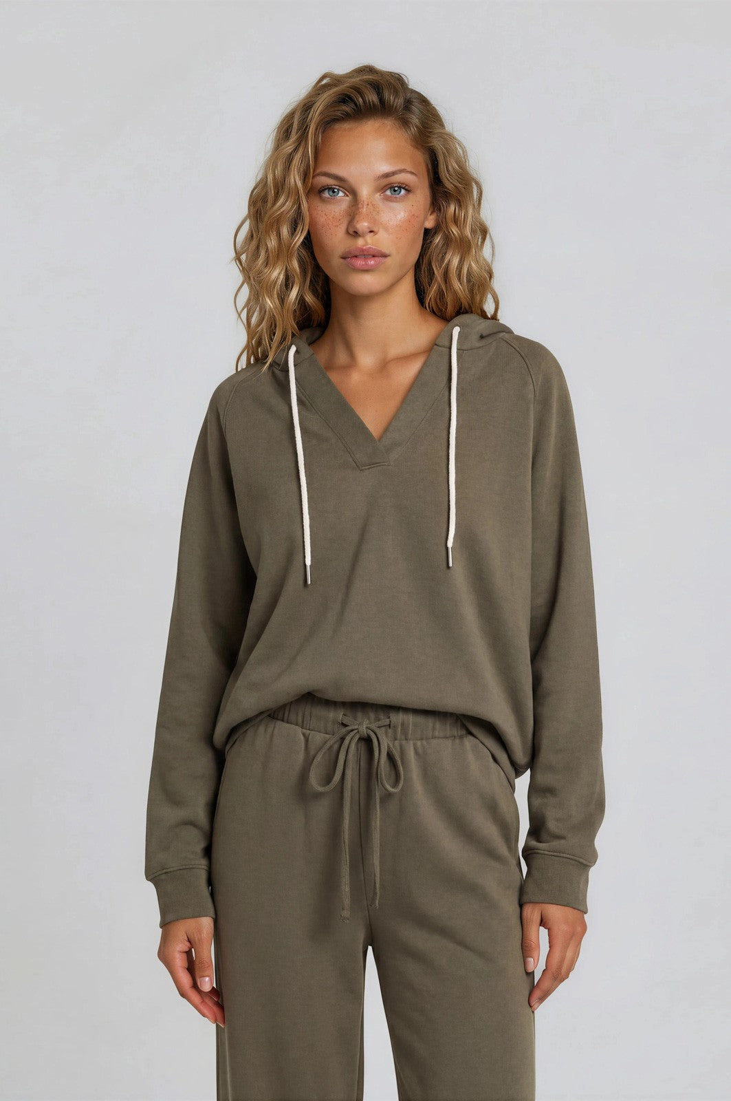 woman wearing an olive green hoodie with a v-neck and drawstring, styled with matching joggers