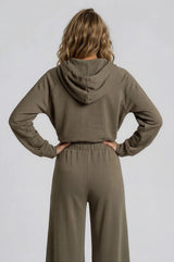 woman wearing a cropped olive green hoodie with a hood and matching high-waisted wide-leg pants from the back