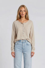 woman wearing a light beige long sleeve henley top with buttons, paired with light wash high-waisted jeans