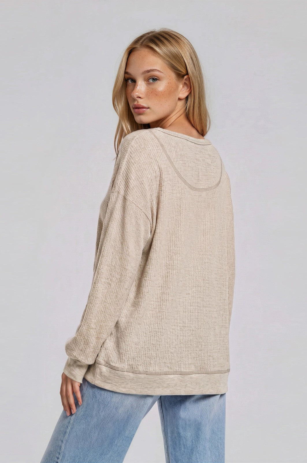 woman wearing a beige loose-fitting long sleeve hoodie with a textured fabric and a relaxed silhouette
